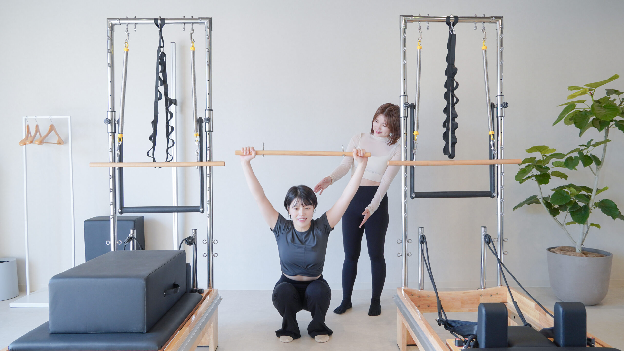 インストラクターが棒を持ってしゃがむ動きを確認する様子